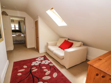 A small sitting area with a white sofa and red floral rug under a skylight at The Barn in Abergavenny