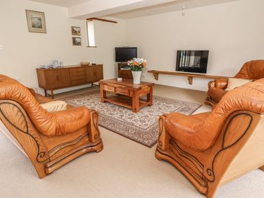 A living room with leather armchairs a wooden coffee table and a sideboard at The Barn in Abergavenny