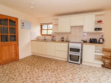 A kitchen with cabinets a stove a sink and appliances at The Barn in Abergavenny
