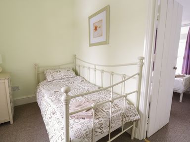 A small bedroom with a single metal bed frame white duvet with text and a folded towel on the bed at Preswylfa in Penmachno