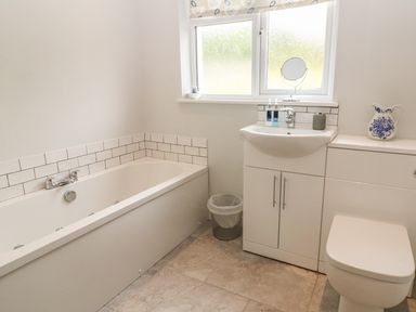 A bathroom with a bathtub sink toilet and window at Cae Glas in Pwllheli