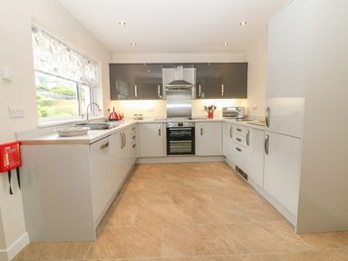 A kitchen with cabinetry appliances oven and a window at Cae Glas in Pwllheli