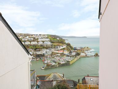 A coastal harbor with boats and houses on a hillside at Pink House in Mevagissey