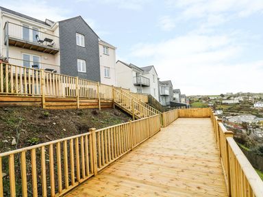 A wooden deck and stairs outside a row of residential buildings at Pink House in Mevagissey