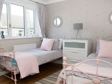 A bedroom with two single beds a white chest of drawers and a lamp at Seashell Cottage in Amble-By-The-Sea
