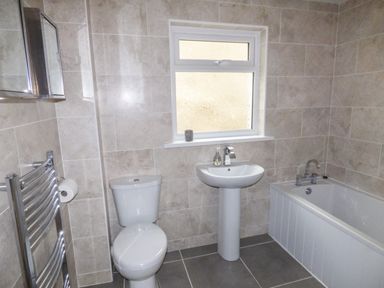A bathroom with a toilet sink bathtub towel rack and a window at Oakdene in Neyland