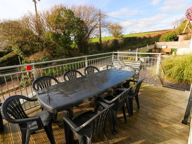 An outdoor patio with a black table surrounded by black chairs and a bench at Oakdene in Neyland