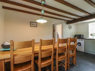 A kitchen with a wooden dining table and chairs at Plas Mawr Groeslon