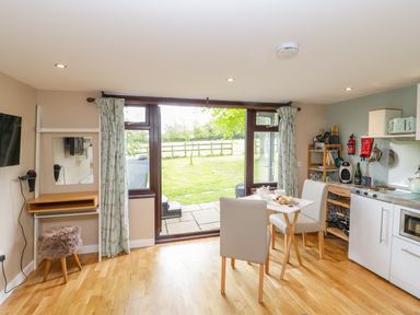 A kitchen dining area with two chairs and table near glass doors opening to a garden at Pheasant Lodge in Wimborne Minster