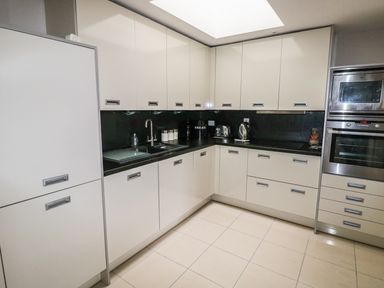 A kitchen with white cabinets black countertops stainless steel oven and microwave in 24 Rhodewood House Saundersfoot