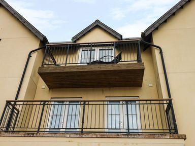 Two balconies with black metal railings on a beige building at 24 Rhodewood House in Saundersfoot