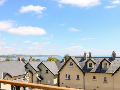 A view of residential houses with grey roofs and chimneys near the coastline with a blue sky at 24 Rhodewood House in Saundersfoot