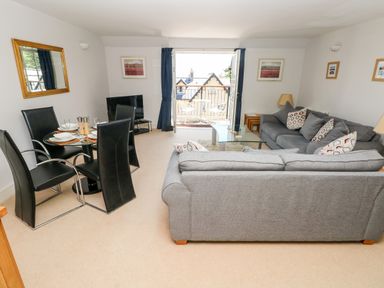 A living room with two grey sofas a glass coffee table and a dining table with black chairs at 24 Rhodewood House in Saundersfoot