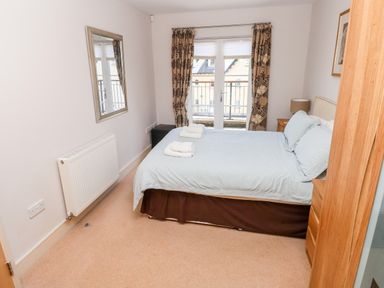 A bedroom with a bed and folded towels on top a mirror on the wall and balcony doors at 24 Rhodewood House in Saundersfoot