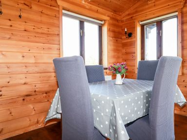 A dining area with a table covered with a star patterned tablecloth and four chairs in a wooden room at Willow Lodge Lanivet near Bodmin