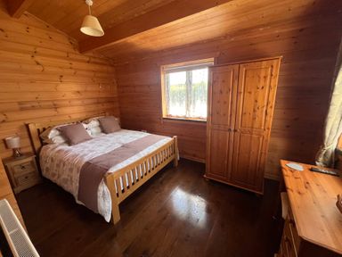 A bedroom with a bed and wardrobe at Holly Lodge in Lanivet near Bodmin