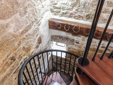 A stone wall with a spiral staircase and horseshoes mounted on a wooden beam at Sunnywell Lanivet near Bodmin