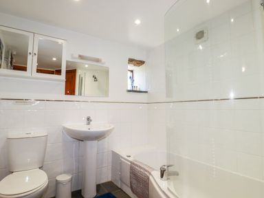 A bathroom with a toilet sink bathtub mirror and small window at Sunnywell Lanivet near Bodmin