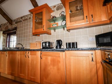 A kitchen with wooden cabinets a toaster kettle bread box and microwave at Sunnywell Lanivet near Bodmin