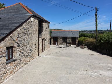 A stone building with slate roof and small patio area with table and chairs at Sunnywell Lanivet near Bodmin