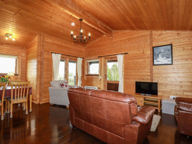 A living room with leather sofas a TV and wooden dining table at Cedar Lodge Lanivet near Bodmin
