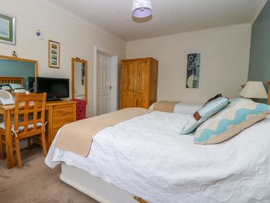 A bedroom with two beds wooden furniture a television and wall art at Richmond Cottage in Burythorpe near Malton