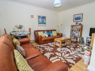 A living room with two brown leather sofas a wooden coffee table bookshelf and a small dining table at Richmond Cottage in Burythorpe near Malton