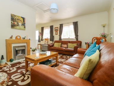 A living room with brown leather sofas a wooden coffee table and a fireplace at Richmond Cottage in Burythorpe near Malton