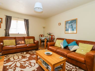 A living room with two leather sofas a wooden coffee table and a small dining table at Richmond Cottage in Burythorpe near Malton