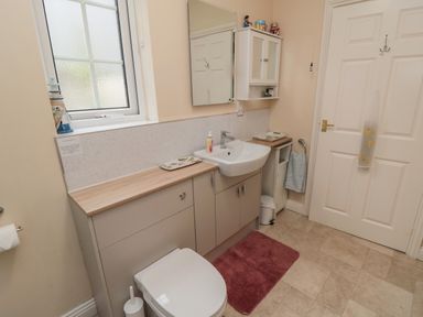 A bathroom with a toilet sink mirror cabinets towel and a window at Richmond Cottage in Burythorpe near Malton