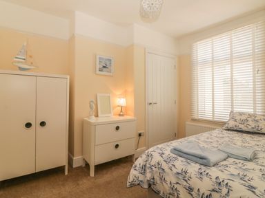 A bedroom with a bed and towel on it a chest of drawers with a lamp sailboat decoration and a wardrobe at Sunvale in Teignmouth