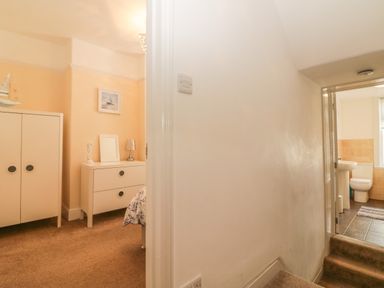 A hallway with stairs leading to a bathroom and a bedroom with a dresser and wardrobe at Sunvale in Teignmouth