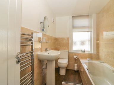 A bathroom with a sink toilet bathtub towel rack and window at Sunvale in Teignmouth