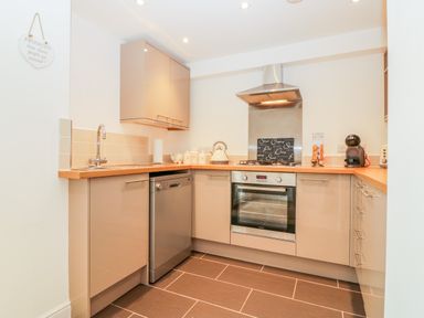 A kitchen with beige cabinets wooden countertops a stainless steel oven stove and hood and a dishwasher at Sunvale in Teignmouth