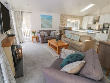 A living room with sofas coffee table and television next to an open kitchen at The Lookout in Stepaside