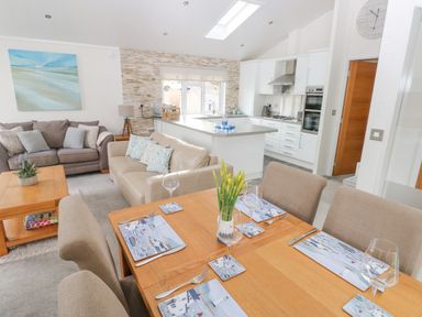A dining table set for four with a vase of flowers in an open plan living room and kitchen at The Lookout in Stepaside