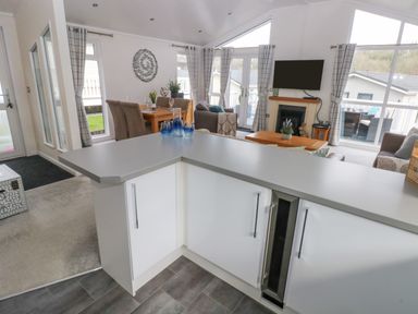 An open kitchen and living area with a dining table chairs and a wall-mounted television at The Lookout in Stepaside