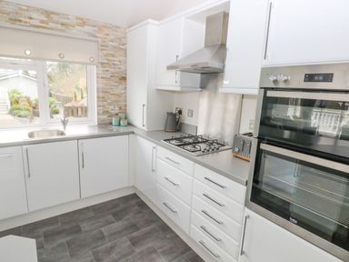 A kitchen with white cabinets a gas stove a double oven a toaster and a window above the sink at The Lookout in Stepaside