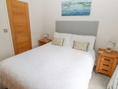 A bedroom with a bed with white bedding two pillows two bedside tables with lamps and a painting above the bed at The Lookout in Stepaside