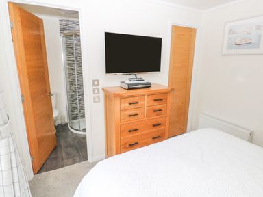 A bedroom with a bed and wooden dresser with a TV on top next to an open door leading to a bathroom at The Lookout in Stepaside