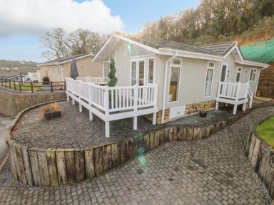 A small house with a white railing deck on a gravel yard beside a paved driveway at The Lookout in Stepaside