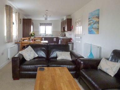 A living room with leather sofas and cushions a wooden coffee table and a dining table with chairs and flowers at Tyack in Charlestown