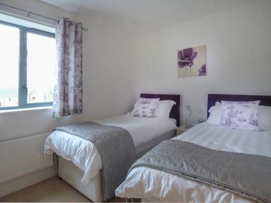 A bedroom with two single beds a window with floral curtains and a bedside table at Tyack in Charlestown
