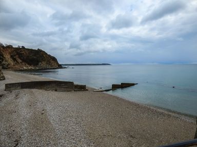 A pebble beach with concrete sea defenses and cliffs under a cloudy sky at Tyack in Charlestown