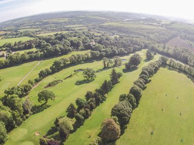 An aerial view of a golf course with trees and green fields at Birch in Truro