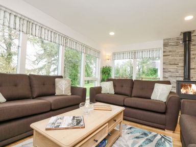 A living room with brown sofas a wooden coffee table and a fireplace at Birch in Truro