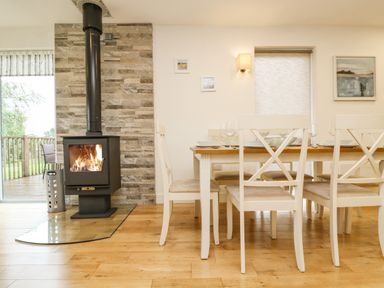 A dining area with a wooden table set for a meal and a wood burning stove against a stone wall at Birch in Truro