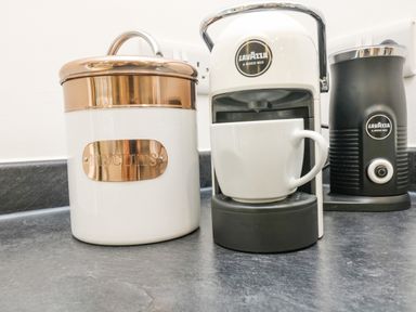 A kitchen counter with a biscuit jar a coffee machine with a cup and a milk frother at Birch in Truro