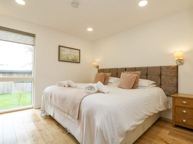 A bedroom with a double bed pillows rolled towels bedside table window and a painting at Birch in Truro