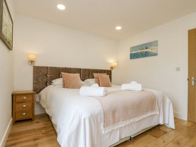A bedroom with a double bed two bedside lamps and wooden floor at Birch in Truro
